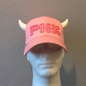 May include: Pink baseball cap with white horns and the word "PNK" in pink letters on the front.
