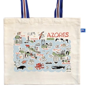 May include: Cream-colored tote bag featuring a map of the Azores islands in Portugal, with blue and red accents. The bag has blue handles with red and white stripes. The word "AZORES" is displayed in red.