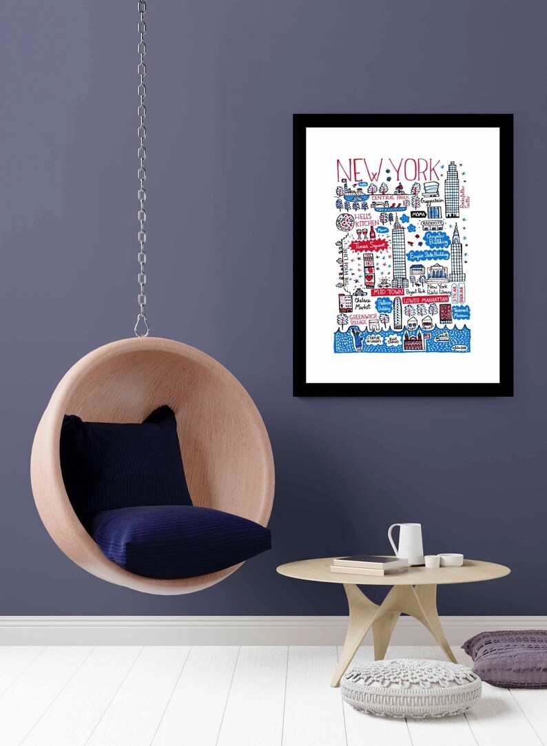 May include: A framed art print featuring a hand-drawn map of New York City in red, blue, and black ink on a white background. The illustration includes labelled landmarks like Central Park, Times Square, and the Statue of Liberty with detailed line work.