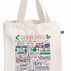 May include: Cream-colored tote bag featuring a colorful illustrated map of Edinburgh, Scotland. The design includes landmarks like the Forth Bridge, Edinburgh Castle, and the Scottish Parliament. The word "EDINBURGH" is at the top. The bag has cream-colored handles.