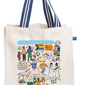Op de afbeelding: Een crèmekleurige canvas draagtas met blauw-wit gestreepte handvatten. De tas heeft kleurrijke illustraties en tekst die gelijkheid, liefde en vriendelijkheid bevorderen, waaronder de woorden "Equality Love Kindness" en "Pride".