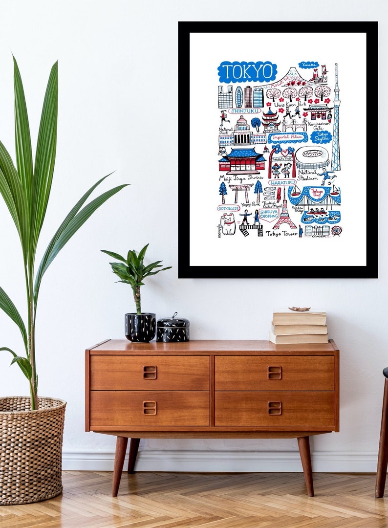 May include: A framed art print featuring a hand-drawn map of Tokyo, Japan. The illustration includes iconic landmarks like Tokyo Tower, Shibuya Crossing, and Meiji Jingu Shrine, rendered in blue, red, and black ink on a white background.