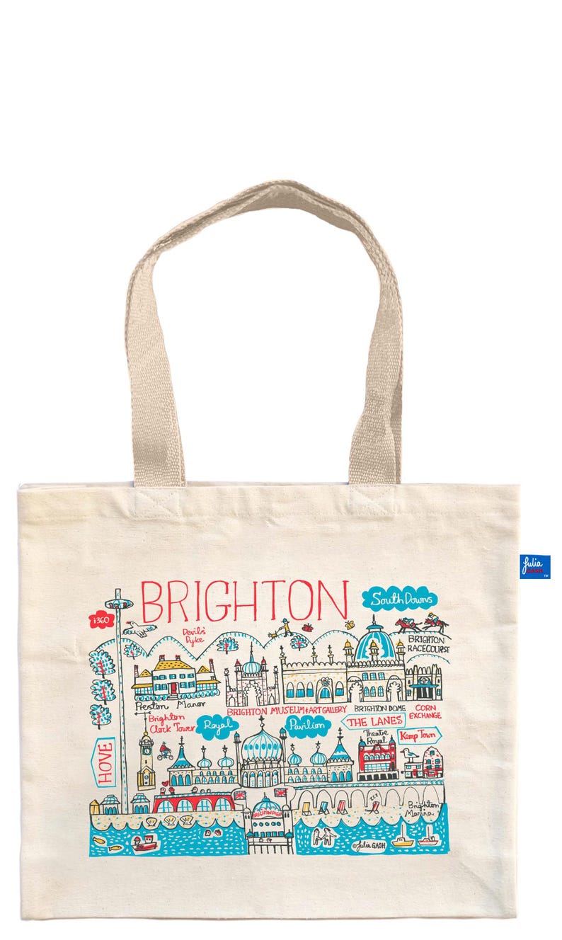 May include: Cream-colored tote bag with a colorful illustration of Brighton landmarks. The design includes the text "BRIGHTON" in red, along with drawings of buildings, the Brighton Racecourse, and the text "HOVE". The bag has beige handles.