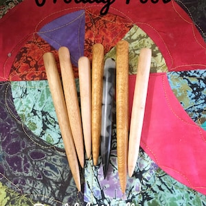 May include: A set of seven wooden tools, including a black and white patterned tool, on a colourful patterned fabric background. The text "Proddy Tool" and "Beautiful Woodturning" are visible in the image.