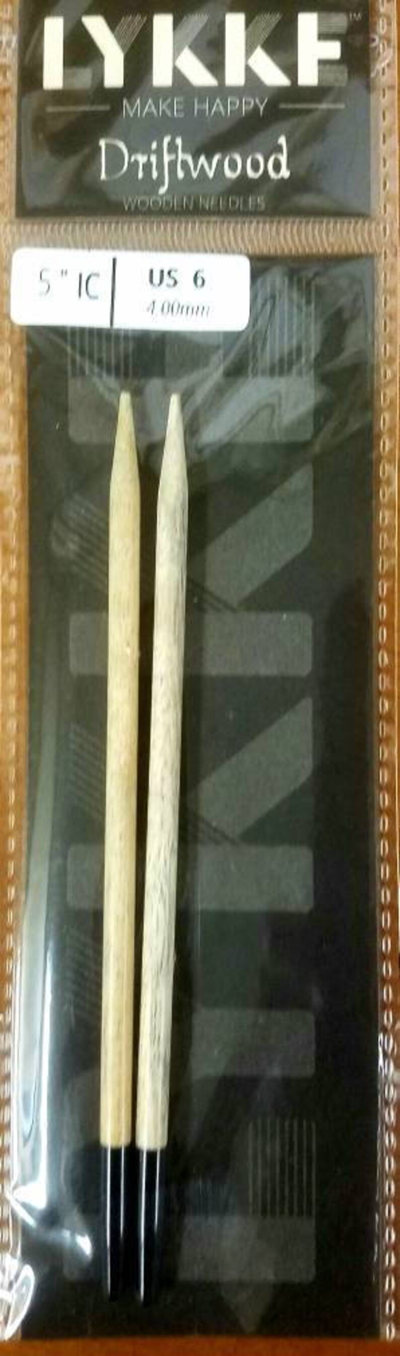 May include: A pair of 5 inch, US size 6,  Lykke Driftwood wooden knitting needles. The needles are natural wood color and have black tips.