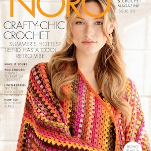 以下が含まれることがあります： カラフルなクロシェのショールを着用した女性が表紙の雑誌。雑誌のタイトルは「Noro」で、表紙のテキストには「Crafty-Chic Crochet」と「夏のトレンドはクールなレトロな雰囲気」と書かれています。