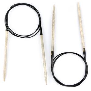May include: A set of two knitting needles, one is a circular needle with a black cable and the other is a straight needle. Both needles are made of wood and have a natural finish.