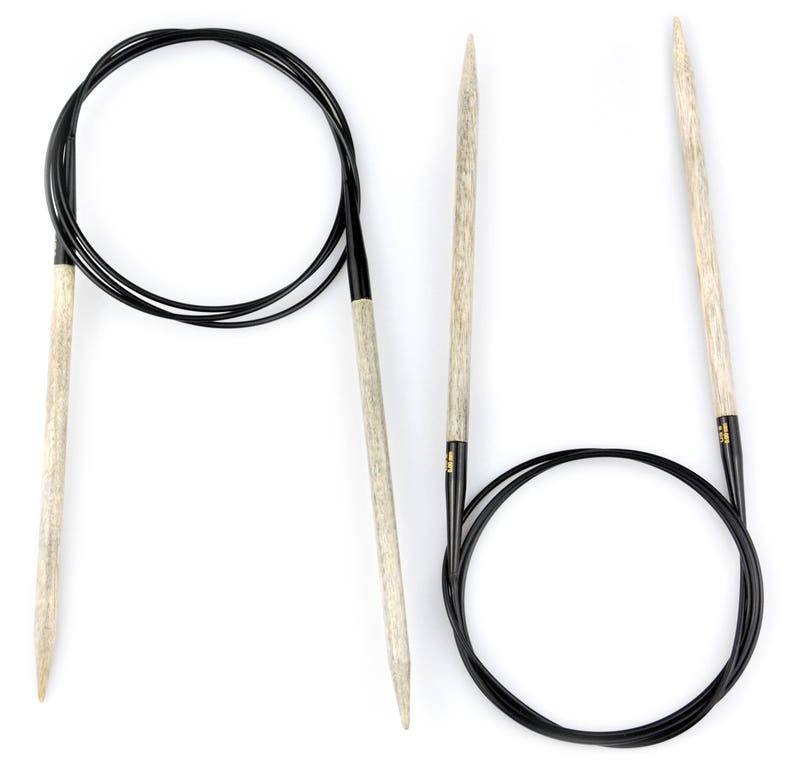 May include: A set of two knitting needles, one is a circular needle with a black cable and the other is a straight needle. Both needles are made of wood and have a natural finish.