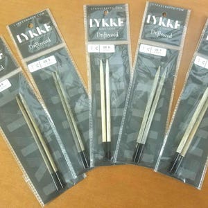 May include: Five pairs of double-pointed knitting needles in various sizes. The needles are made of wood and have a natural driftwood finish. The packaging is labeled "Lykke Driftwood" and includes the size of the needles in both US and metric sizes.