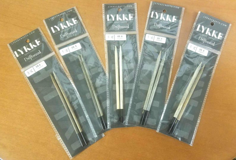 May include: Five pairs of double-pointed knitting needles in various sizes. The needles are made of wood and have a natural driftwood finish. The packaging is labeled "Lykke Driftwood" and includes the size of the needles in both US and metric sizes.