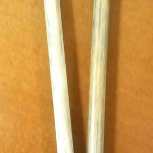 May include: Two wooden knitting needles with black tips. The needles are approximately 12 inches long.