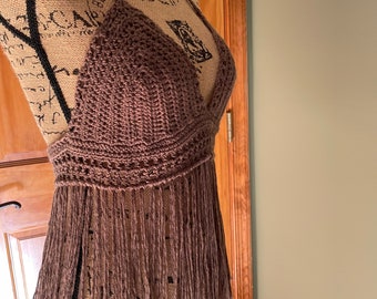 May include: A brown crocheted halter top with fringe. The top is on a dress form.