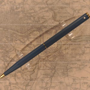 May include: A blue ballpoint pen with a gold trim and a white dot on the top.