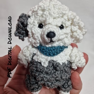 May include: A handmade crochet dog with white, gray, and teal accents. The dog has a fluffy white head and body, gray ears and overalls, and a teal scarf. The text "PDF DIGITAL DOWNLOAD" is on the left side.