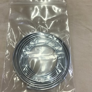 May include: A roll of silver trim in a clear plastic bag. The trim is coiled and ready to be used for decorative purposes.