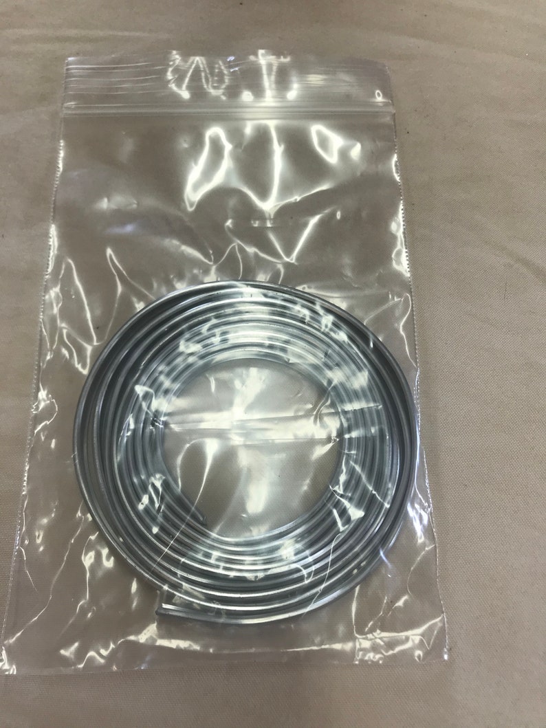 May include: A roll of silver trim in a clear plastic bag. The trim is coiled and ready to be used for decorative purposes.