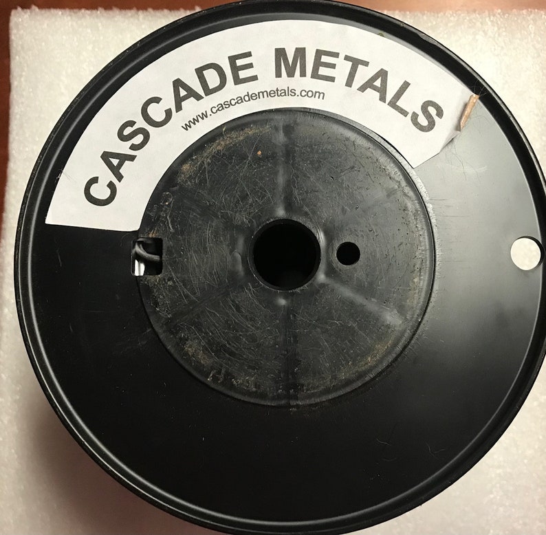 May include: A black spool of wire with a white label that says "CASCADE METALS" and "www.cascademetals.com".