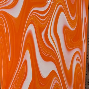 May include: Orange and white swirled glass sheet. The glass has a glossy finish and a flowing, marbled pattern. The design features broad, curving bands of orange and white, creating a dynamic visual effect. The sheet is rectangular.