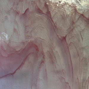 May include: A close-up of a pink and white marbled glass surface. The surface has a swirling, abstract pattern.