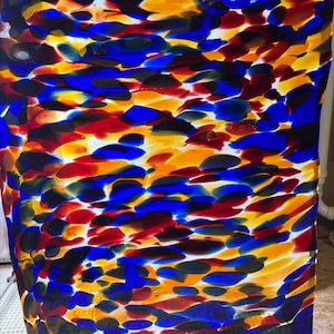 May include: A rectangular glass panel featuring a vibrant, multi-colored abstract pattern of overlapping blue, red, yellow, and black organic shapes. The surface has a smooth, glossy finish with a semi-translucent quality that allows light to pass through.