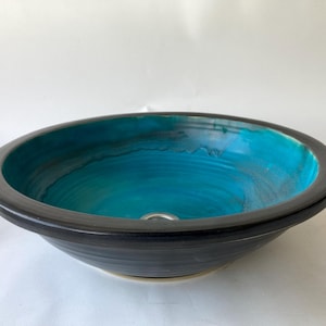 Può includere: Una tazza di ceramica bianca con un manico nero e la scritta "But First, Coffee" in nero, con un carattere a mano. La tazza è su una superficie bianca.