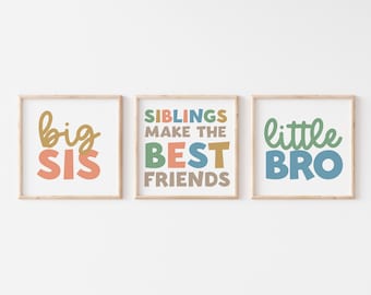 May include: Three framed prints with colorful text. The left print says "big sis" in gold and pink. The middle print says "Siblings make the best friends" in various colors. The right print says "little bro" in green and blue.