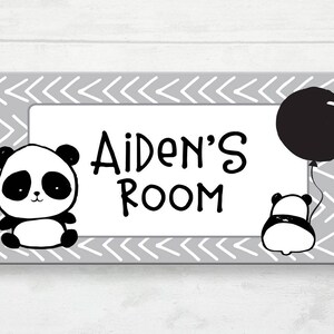 May include: A rectangular sign with a grey chevron border and a white interior. The sign reads "Aiden's Room" in black text and features two panda illustrations, one holding a black balloon. The design is playful and suitable for a child's room.
