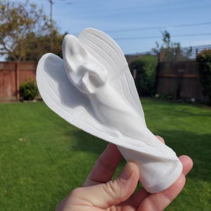 Può includere: Figurina di angelo in ceramica bianca con le ali spiegate. L'angelo è scolpito a forma di spirale.