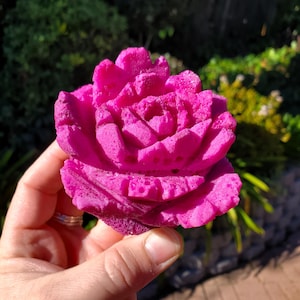 May include: A bright pink, detailed, 3D printed rose. The rose is made of a textured material and has a realistic appearance.