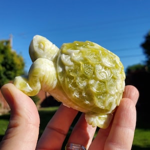 May include: A green jade turtle sculpture with intricate details. The turtle is carved with a detailed shell and has a realistic appearance.