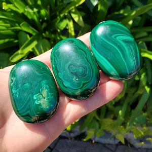 Può includere: Tre pietre di malachite lisce di forma ovale con motivi a spirale verde e marrone. Le pietre sono lucidate e hanno una finitura lucida.