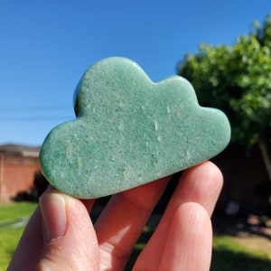 May include: A green cloud-shaped stone carving. The stone has a smooth, polished surface and a light green color.