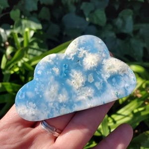 May include: A blue and white cloud-shaped piece of celestite crystal. The crystal has a cloudy, opaque appearance with white inclusions.