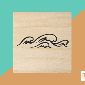 Könnte beinhalten: Ein Stempel aus Holz mit einer schwarzen Umrandung von stilisierten Wellen. Der Stempel ist leer und bereit zur Verwendung.