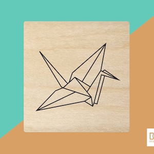 May include: A wooden stamp with a black line drawing of an origami crane.