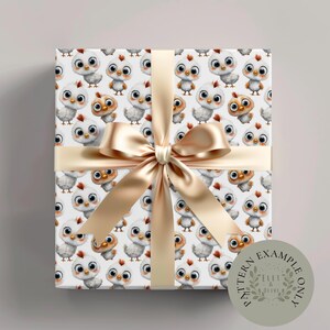 May include: A wrapped gift box featuring a repeating pattern of cartoon chicks in white, gray, and brown on a white background. The box is tied with a gold satin ribbon and bow. A circular sticker with the text "PATTERN EXAMPLE ONLY" is on the bottom right.