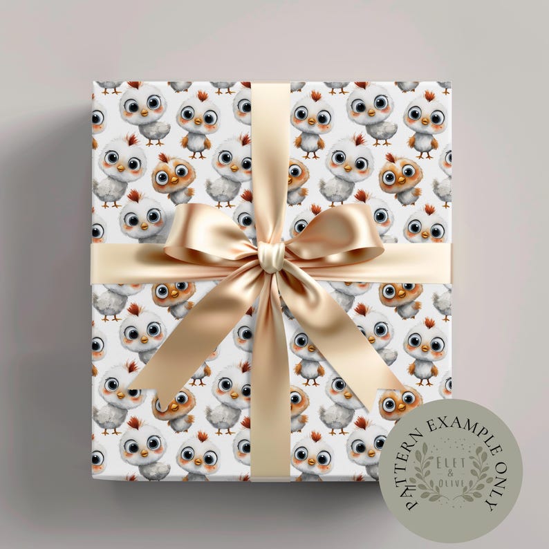 May include: A wrapped gift box featuring a repeating pattern of cartoon chicks in white, gray, and brown on a white background. The box is tied with a gold satin ribbon and bow. A circular sticker with the text "PATTERN EXAMPLE ONLY" is on the bottom right.