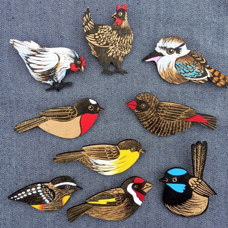 May include: A set of nine wooden bird and chicken ornaments. The ornaments are painted in various colors, including black, white, red, yellow, blue, and brown. The ornaments are all different shapes and sizes, and they are all very detailed.