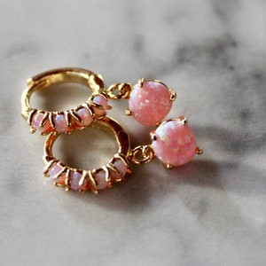 May include: A pair of gold hoop earrings with pink opal stones. The hoops are adorned with smaller pink opal stones.