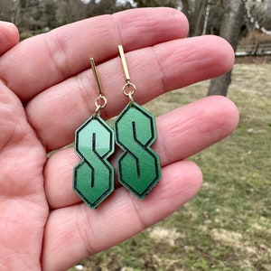 May include: A pair of green gradient earrings shaped like the letter 'S' with gold hooks.