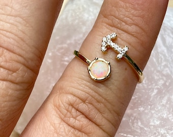 May include: Gold ring with a white opal stone and a Sagittarius zodiac symbol with small clear stones.