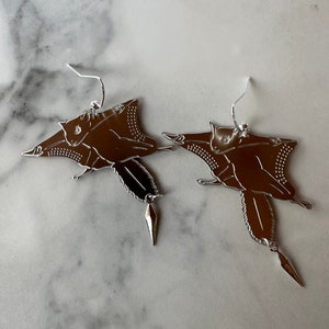 May include: A pair of silver earrings featuring a flying squirrel design with a dangling crystal accent.