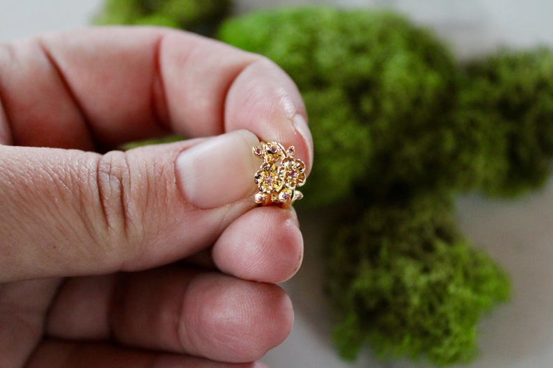 May include: A gold-toned butterfly charm with pink accents. The charm is detailed with intricate designs and is perfect for adding a touch of whimsy to jewelry.