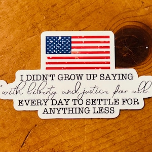 May include: A white sticker with the American flag and the text "I didn't grow up saying with liberty and justice for all every day to settle for anything less."