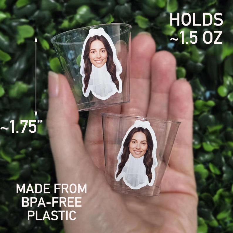 May include: Two clear plastic shot glasses, each featuring a sticker of a person wearing a white bridal veil. The cups are 1.75 inches tall, hold 1.5 ounces, and are made from BPA-free plastic. The design shows a smiling face with long brown hair.