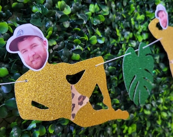 Puede incluir: Una pancarta de fiesta de purpurina dorada con un recorte de una persona con un traje de baño y un recorte de cara. La pancarta está decorada con hojas verdes.