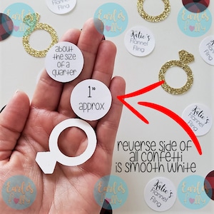 May include: White confetti with a ring design, approximately 2.5 cm in diameter. The confetti is about the size of a 25 pence coin. The reverse side of the confetti is smooth white.