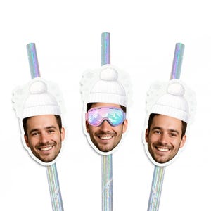 May include: Three decorative straws with smiling faces. Two straws have a white knit cap with a pom-pom, and one has ski goggles. The straws are iridescent with a silver sheen, perfect for a winter-themed party.