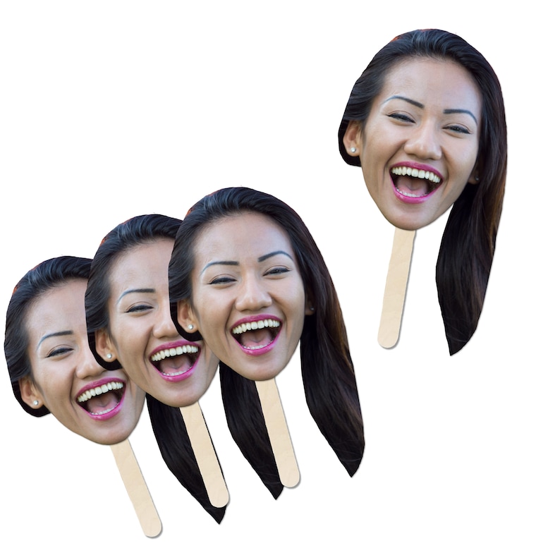 May include: Four paper face cutouts on sticks, featuring a woman with long dark hair laughing. The cutouts are printed with a photo of the woman's face.