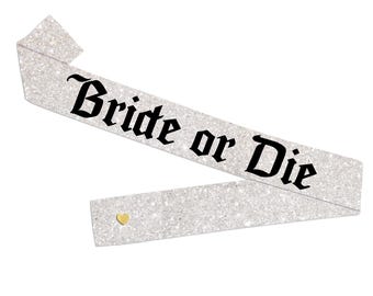 May include: A glittery silver sash with the phrase "Bride or Die" in black gothic lettering. A small gold heart is affixed near the bottom of the sash. This accessory is perfect for a bachelorette party or bridal event.